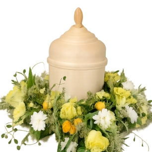 En beige urna omgiven av en krans av vita och gula blommor mot en vit bakgrund.