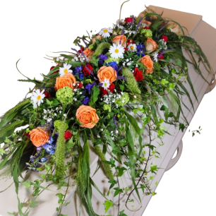 Färgglad blomsterdekoration med orange rosor, prästkragar och grönt lövverk på en kista.